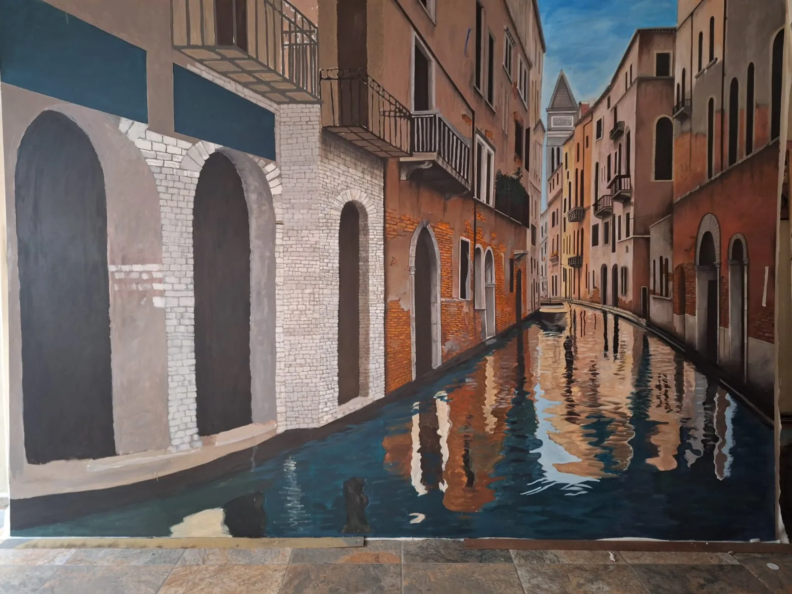 Mural de un canal veneciano con fachadas de ladrillo reflejadas en el agua.